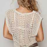 Woman wearing a beige knitted shrug over a dress against a plain background