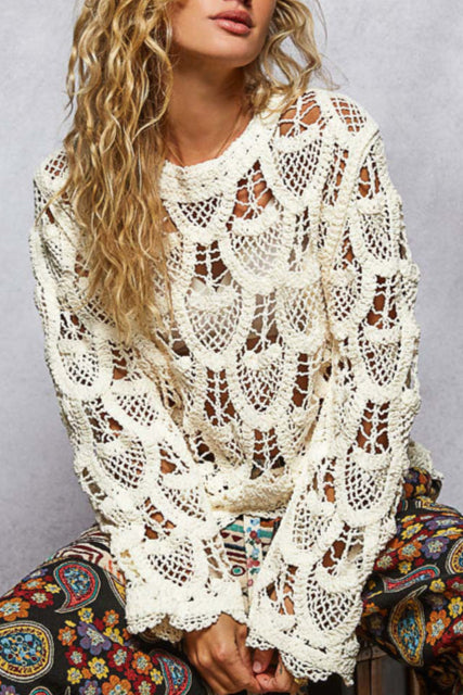 Woman wearing a white lace top with colorful pants against a gray background