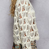 Woman wearing a white crochet top against a gray background