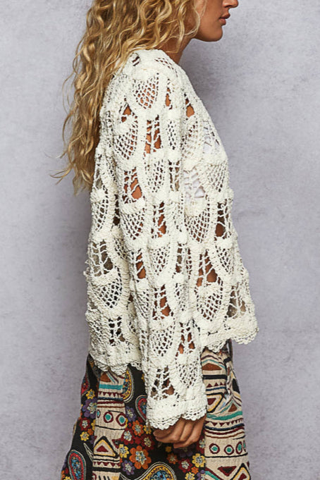 Woman wearing a white crochet top against a gray background