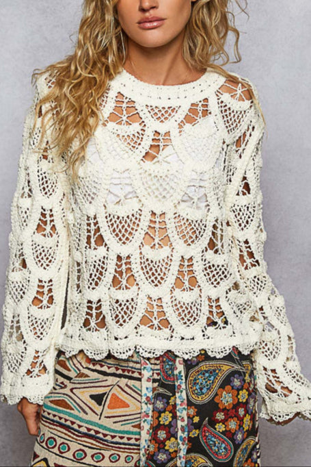 Woman wearing a white lace top with colorful pants against a gray background