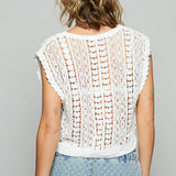 Person wearing a white crochet top and denim skirt on a gray background