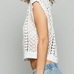 Woman wearing a white crochet top against a gray background