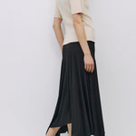 Woman wearing a beige top and black skirt on a white background