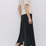 Woman wearing a beige top and black skirt on a white background