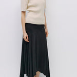 Woman wearing a beige top and black skirt against a white background