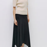 Woman wearing a beige top and black skirt against a white background