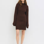 Woman wearing a brown knit dress against a white background