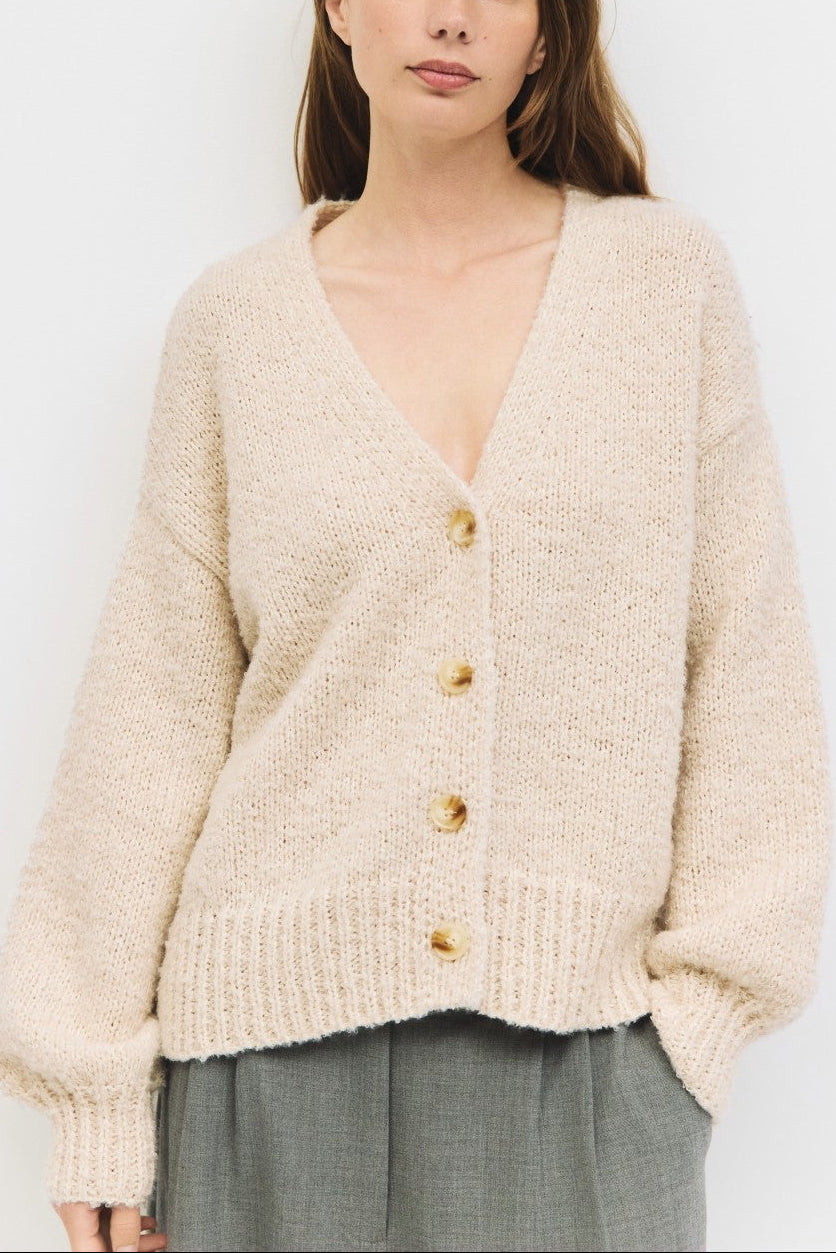 Woman wearing a beige cardigan against a white background