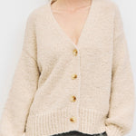 Woman wearing a beige cardigan against a white background