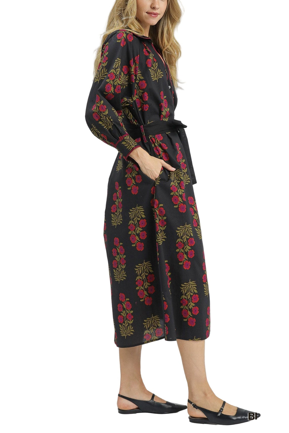 Woman wearing a black dress with red floral patterns on a white background