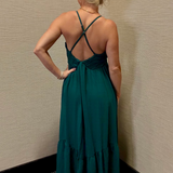 Woman in a green dress standing against a beige wall.