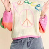 Person wearing a colorful sweater with 'peace' text and design