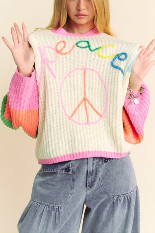 Person wearing a colorful sweater with 'peace' text and design