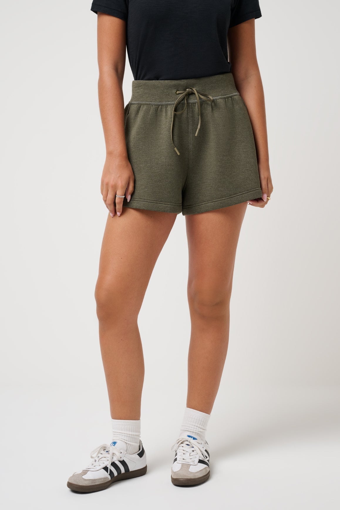 Person wearing olive green shorts on a white background