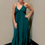 Woman in a teal dress standing against a beige wall.