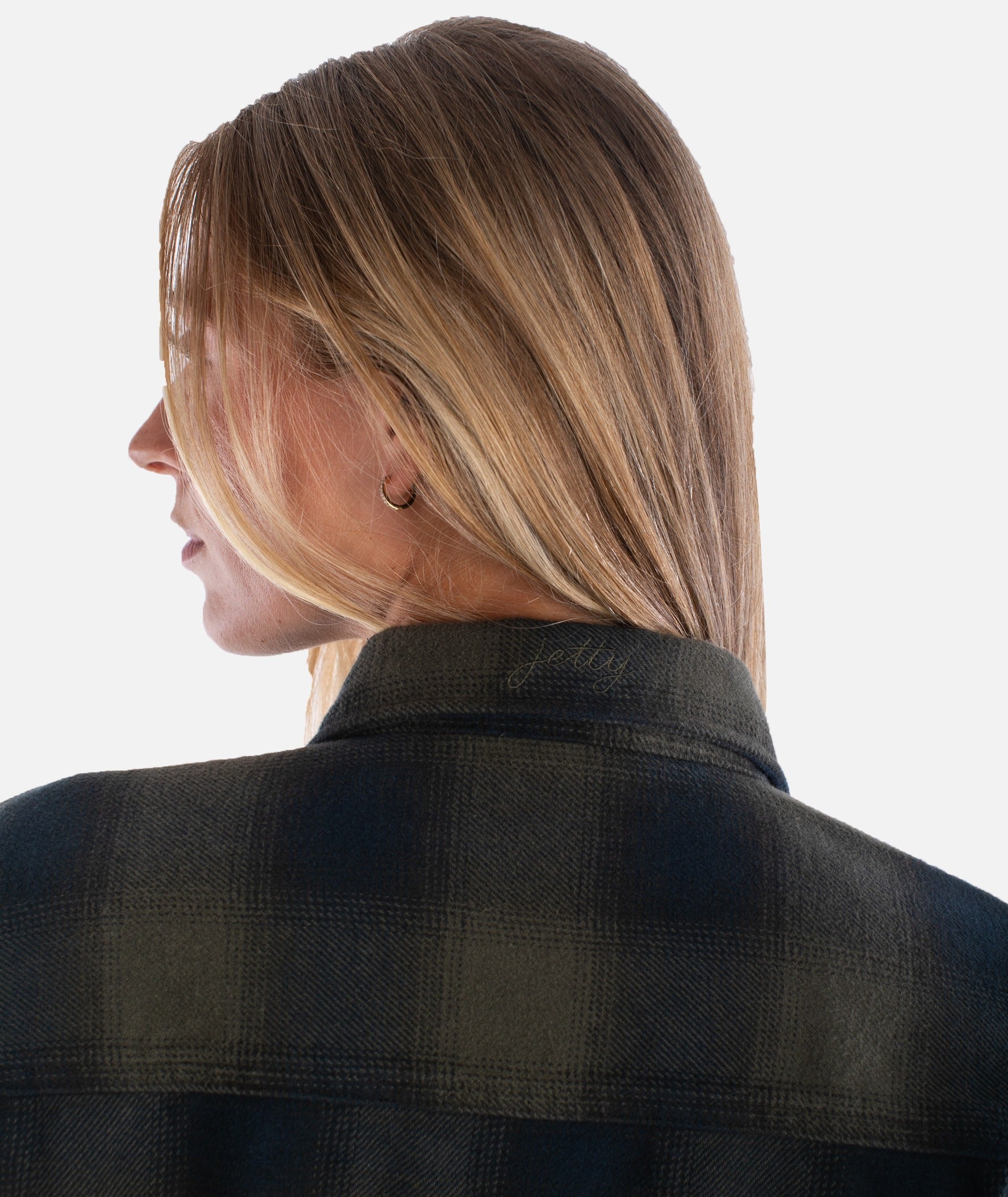 Person wearing a black plaid shirt with a plain background