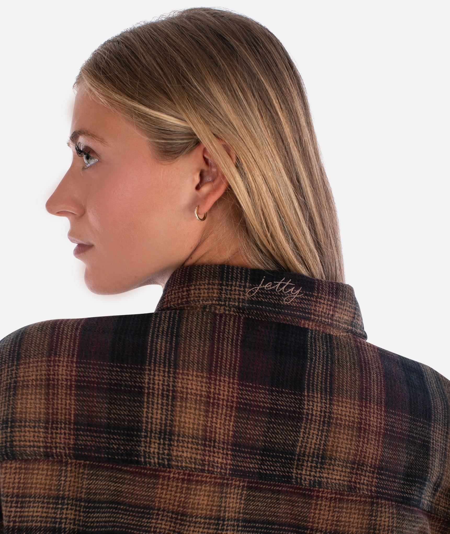 Person wearing a plaid shirt with 'Jettly' branding on the collar against a white background