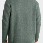 Green sweater worn by a person on a white background