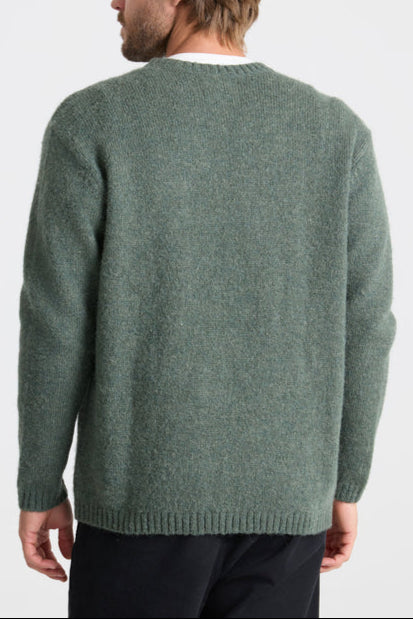 Green sweater worn by a person on a white background