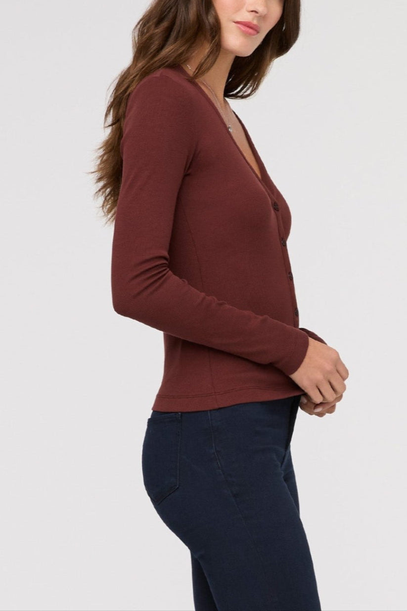 Woman wearing a brown long-sleeve top against a white background