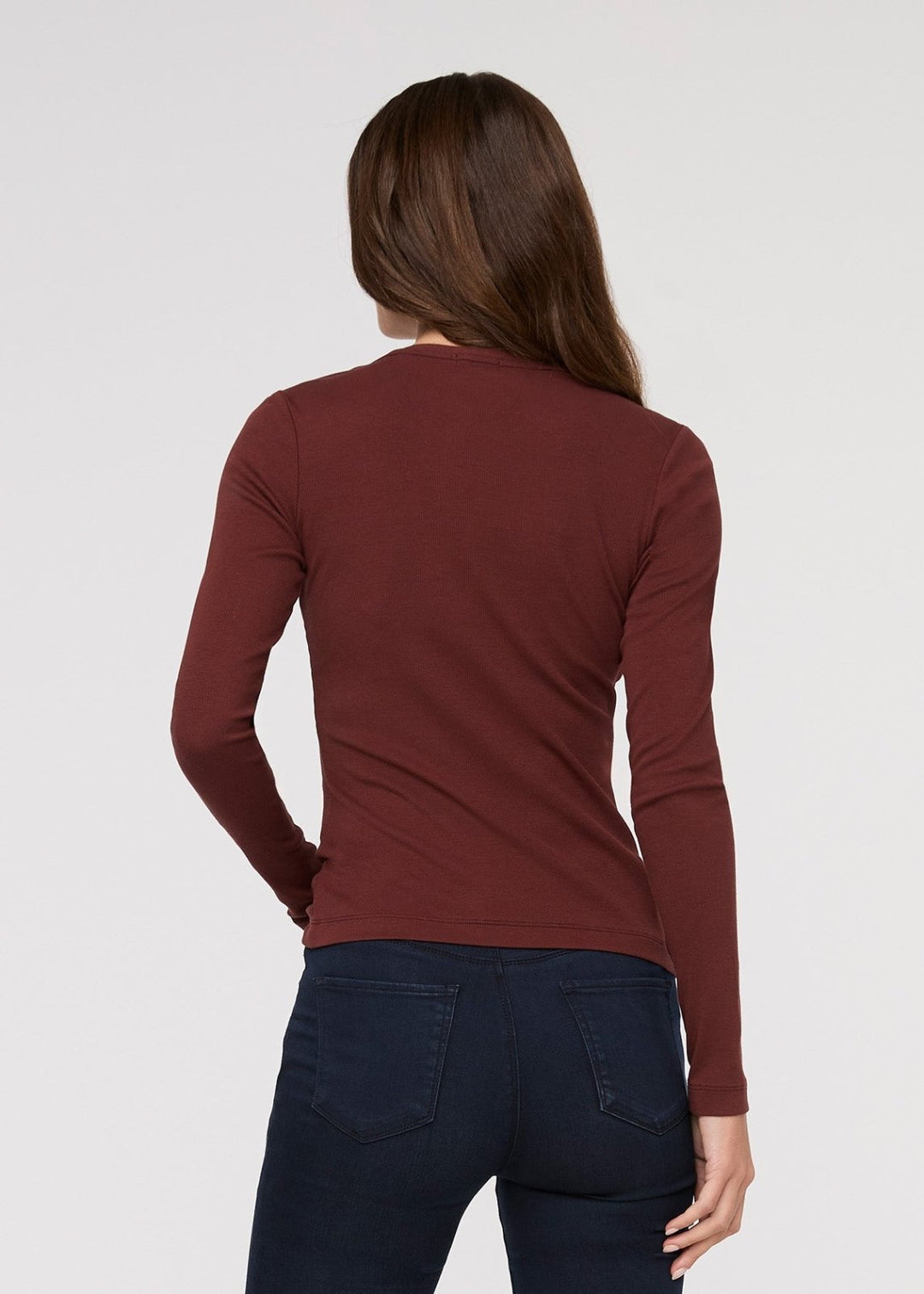 Person wearing a maroon long-sleeve shirt and dark pants on a white background