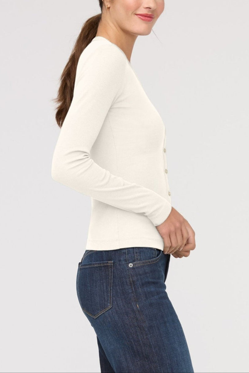 Woman wearing a white long-sleeve top and blue jeans on a light gray background