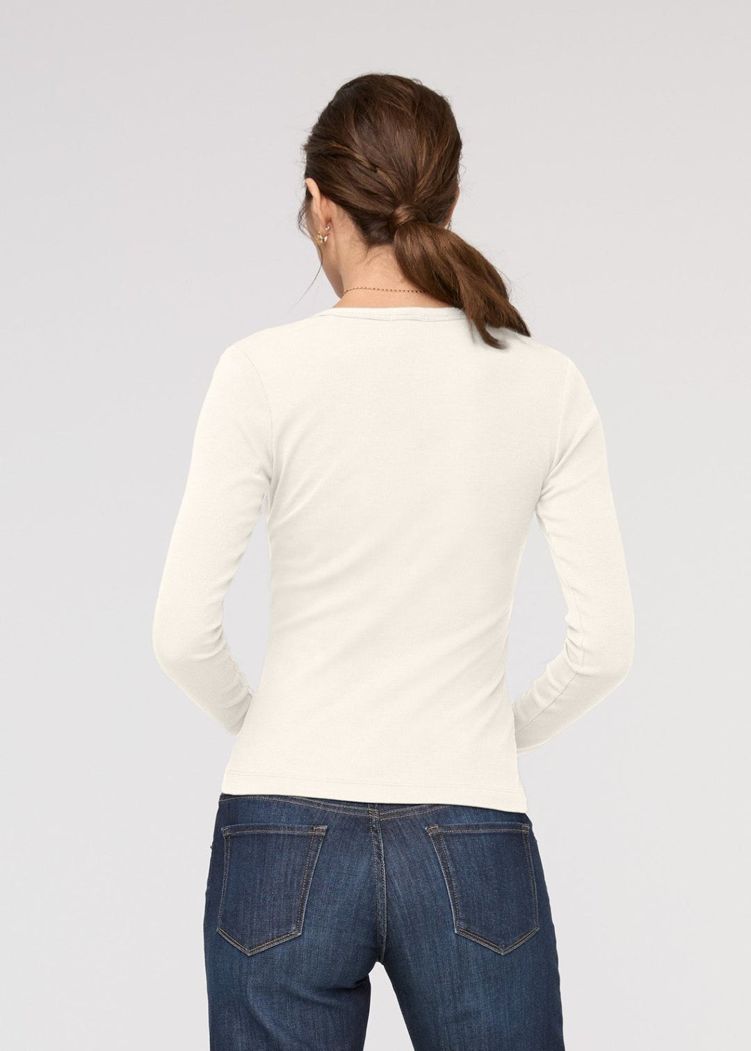 Person wearing a white long-sleeve shirt and blue jeans on a light gray background