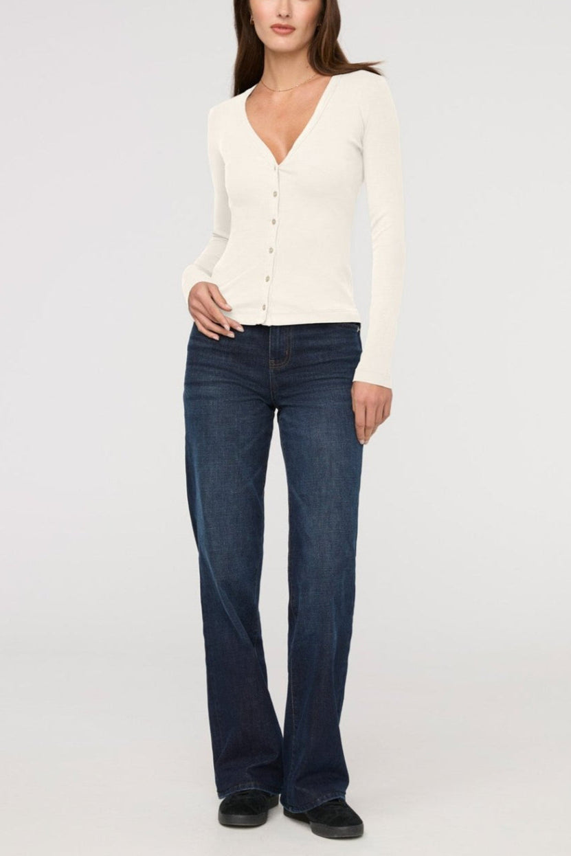 Woman wearing a white cardigan and dark blue jeans on a white background
