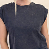 Person wearing a dark blue distressed t-shirt and shorts on a beige background