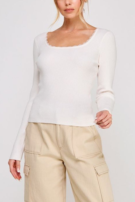 Woman wearing a white long-sleeve top and beige pants on a plain background