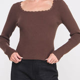 Woman wearing a brown sweater with a plain background
