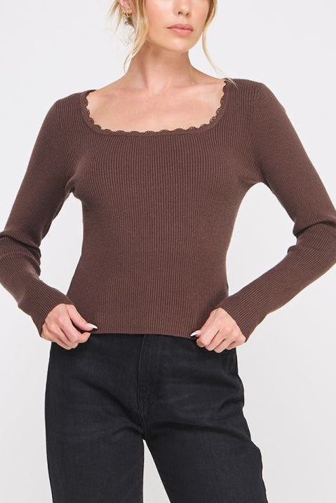 Woman wearing a brown sweater with a plain background