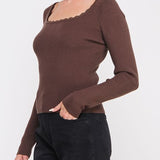Woman wearing a brown long-sleeve top with a plain background