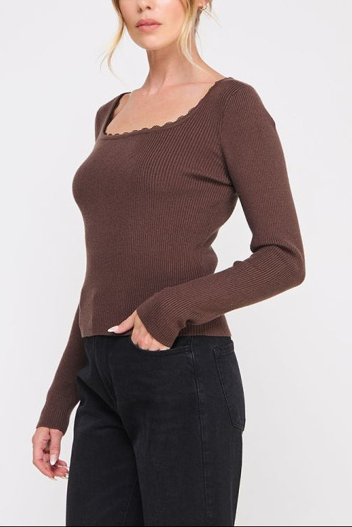 Woman wearing a brown long-sleeve top with a plain background