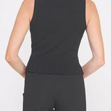Woman wearing a black sleeveless top and black pants on a white background