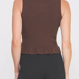 Woman wearing a brown sleeveless top and black pants on a white background