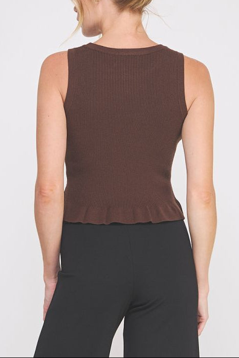 Woman wearing a brown sleeveless top and black pants on a white background