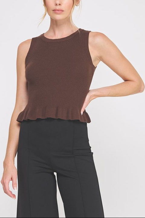 Woman wearing a brown sleeveless top and black pants on a white background