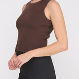 Woman wearing a brown sleeveless top and black pants on a white background