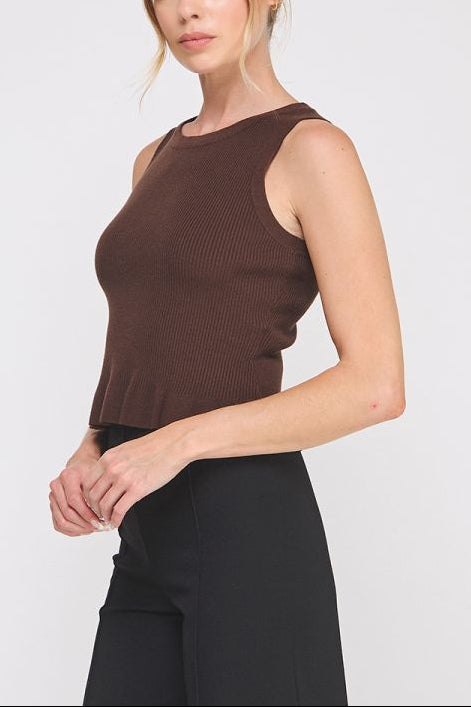Woman wearing a brown sleeveless top and black pants on a white background