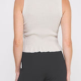 Woman wearing a beige sleeveless top and black pants on a white background