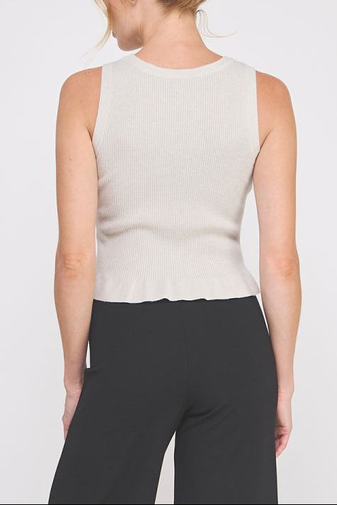 Woman wearing a beige sleeveless top and black pants on a white background