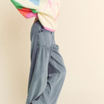 Person wearing a colorful sweater and blue jeans on a plain background