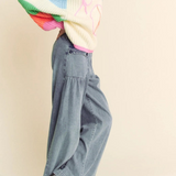 Person wearing a colorful sweater and blue jeans on a plain background