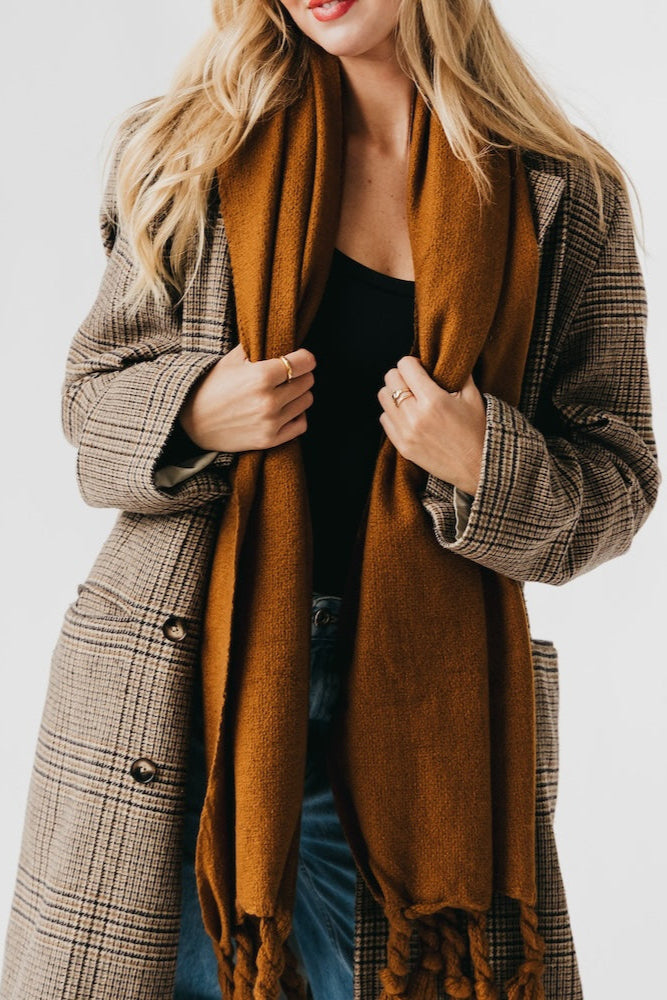 Person wearing a plaid coat and brown scarf against a white background