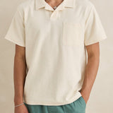 Man wearing a beige polo shirt and green pants against a beige background