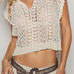Woman wearing a beige crochet top and skirt with a belt against a plain background