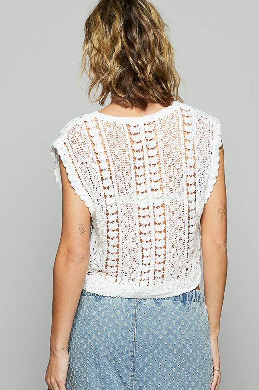Person wearing a white crochet top and denim skirt on a gray background