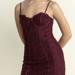 Woman wearing a burgundy lace dress against a plain background